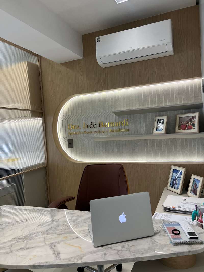 Sala de atendimento com nicho iluminado na parede, poltrona e mesa de mármore