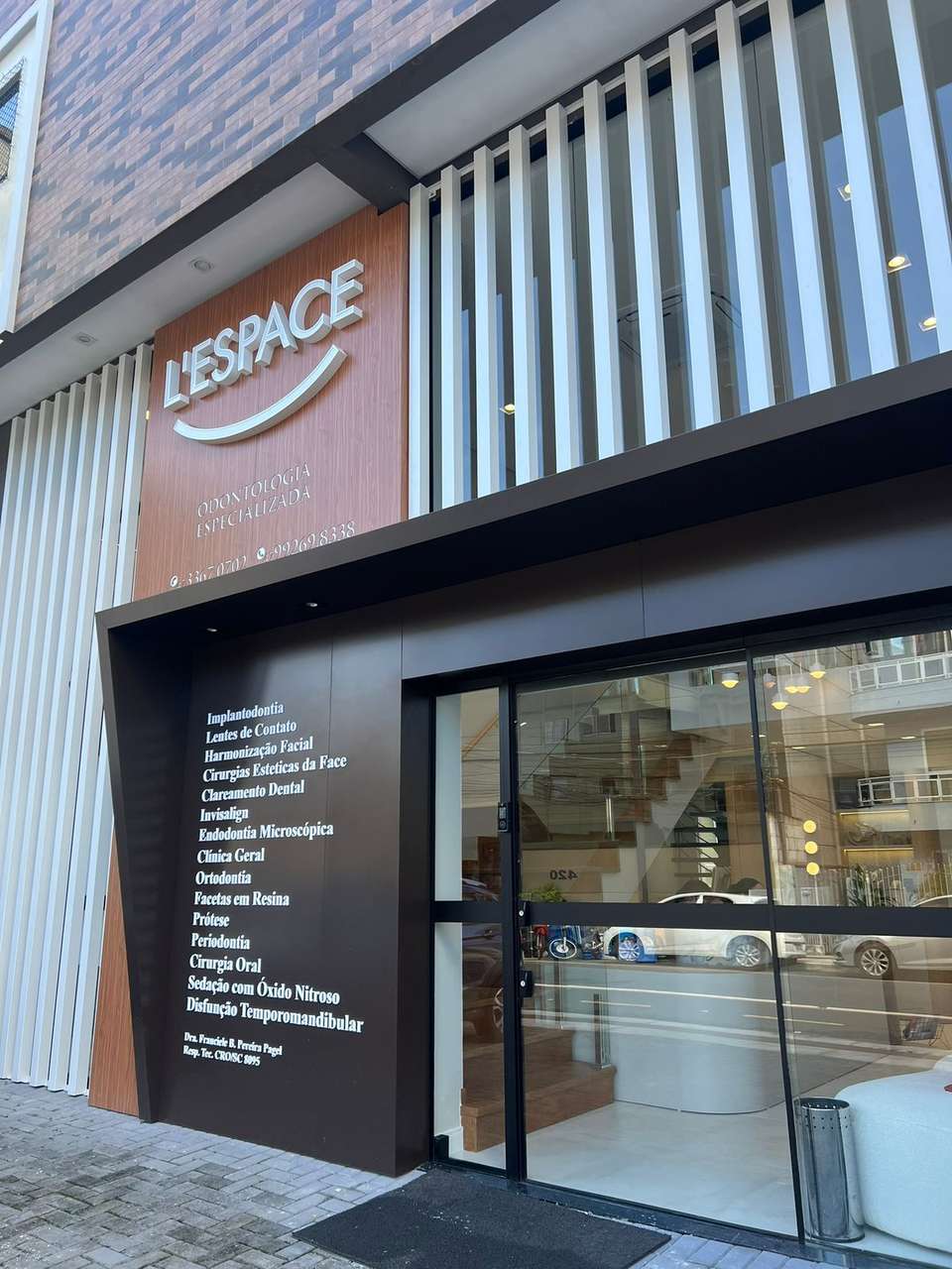 Fachada da L'Espace na Rua 3208, com letreiro, lista de áreas e porta de vidro